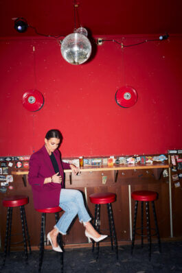 Laura Wontorra an der Bar mit Diskokugel vor rotem Hintergrund